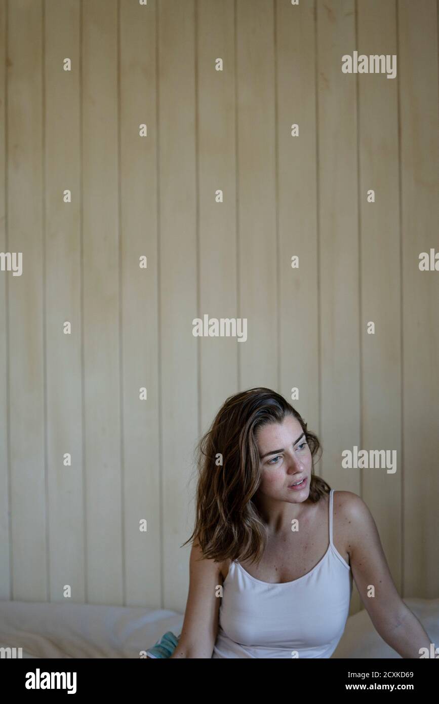 Beautiful young woman sitting on bed Stock Photo