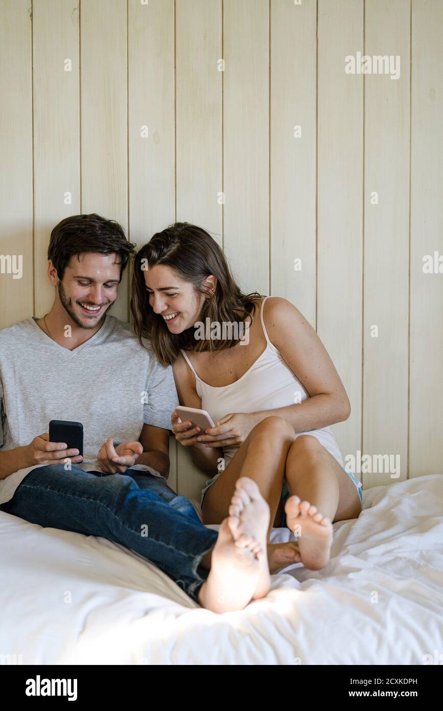 Young couple using smartphones in bedroom Stock Photo