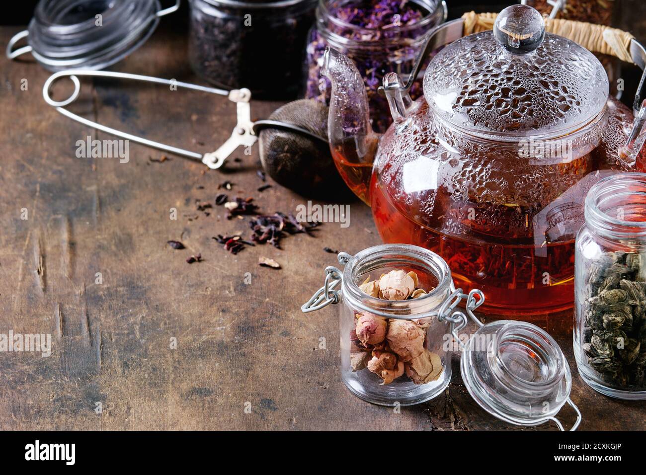 https://c8.alamy.com/comp/2CXKGJP/variety-of-black-green-and-herbal-dry-tea-leaves-in-glass-jars-with-vintage-strainer-and-teapot-of-hot-tea-over-old-dark-wooden-background-close-up-2CXKGJP.jpg