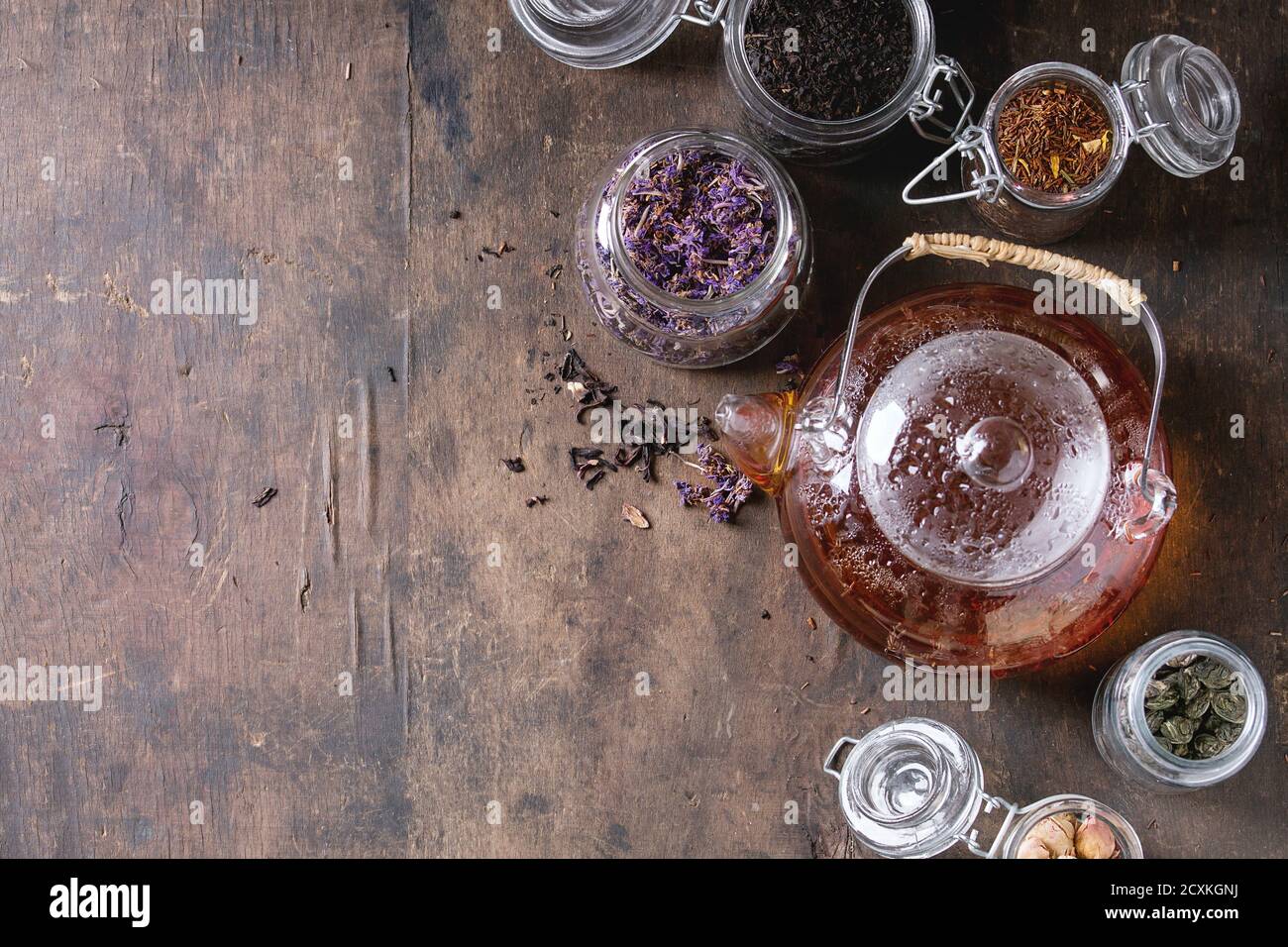 https://c8.alamy.com/comp/2CXKGNJ/variety-of-black-green-and-herbal-dry-tea-leaves-in-glass-jars-with-vintage-strainer-and-teapot-of-hot-tea-over-old-dark-wooden-background-top-view-2CXKGNJ.jpg