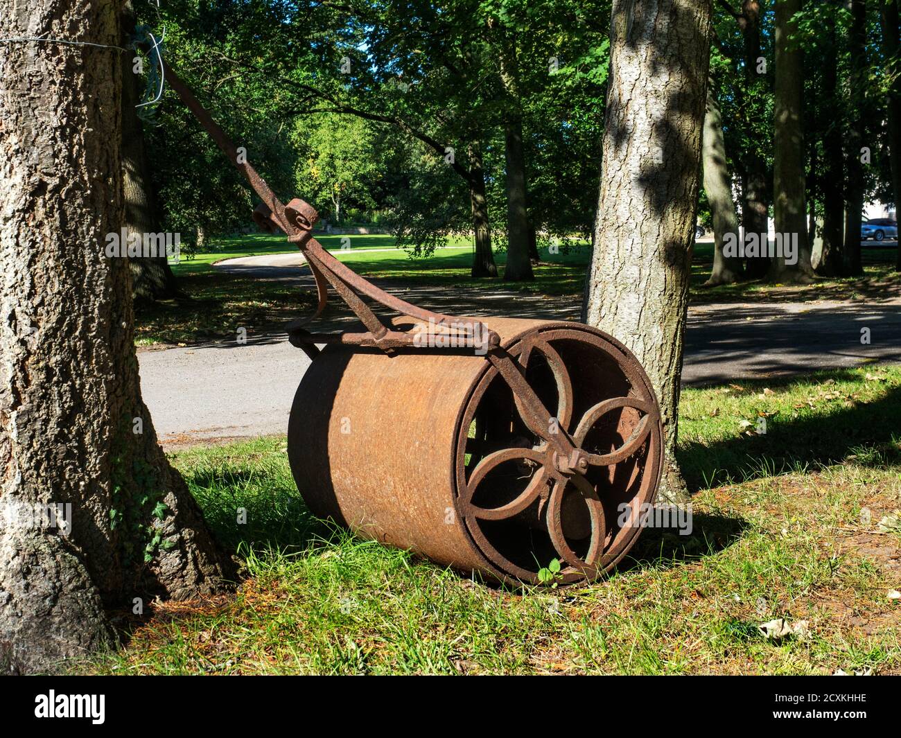 Rusty grass roller under trees at the entrance to Allerton Park in Allerton Mauleverer near Knaresborough North Yorkshire England Stock Photo
