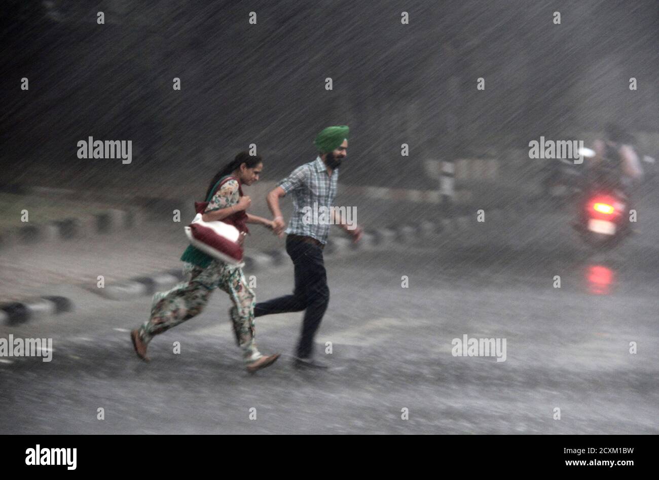 Commuters run for cover as they cross a road during monsoon rains in the  northern Indian city of Chandigarh July 6, 2012. The June-September monsoon  rains, the main source of water for