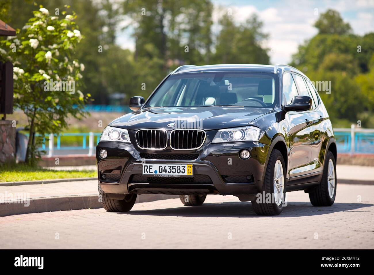 GRODNO, BELARUS - JUNE 2020: BMW X3 II F25 2.0i xDrive front three fourth view outdoors on sunny road background of summer city promenade flowering Stock Photo