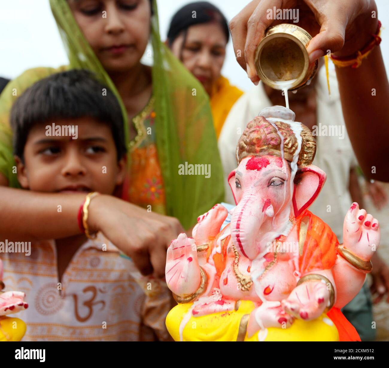 A Hindu devotee pours milk on a murti of Lord Ganesha during the Ganesh Utsav festival at Chagville beach in Chaguaramas September 15, 2013. REUTERS/Andrea De Silva (TRINIDAD AND TOBAGO - Tags: RELIGION SOCIETY) Stock Photo
