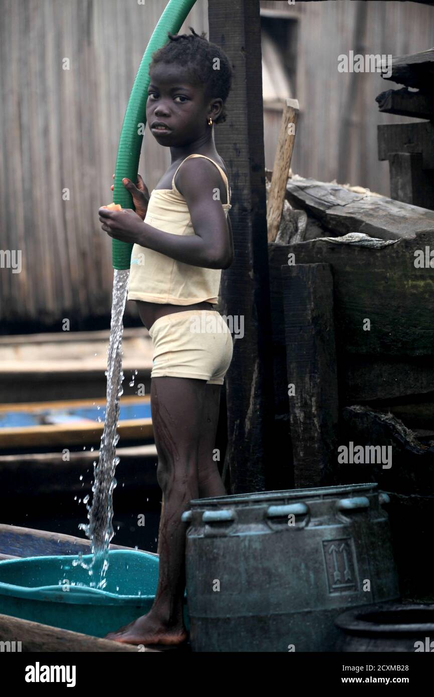 A girl fetches water from a hose in the Makoko fishing community in  Nigeria's commercial capital Lagos January 22, 2011. REUTERS/Akintunde  Akinleye (NIGERIA - Tags: SOCIETY Stock Photo - Alamy