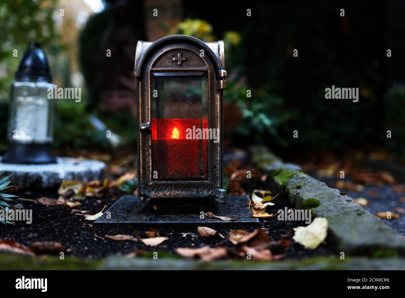 old grave lantern with burning candle at dusk on a cemetery in autumn Stock Photo