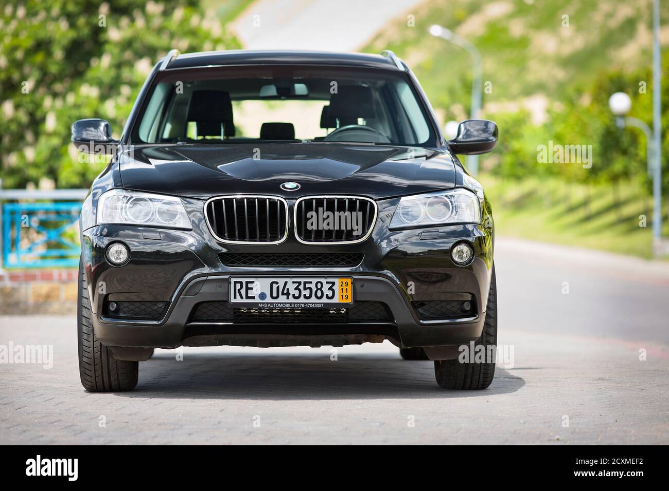 GRODNO, BELARUS - JUNE 2020: BMW X3 II F25 2.0i xDrive selective focus front view outdoors on sunny road background of summer city promenade flowering Stock Photo