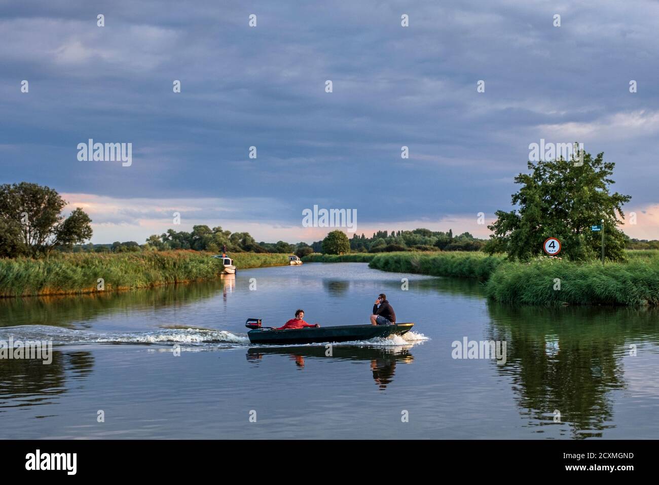 A motorboat sailing along the River Bure near St. Benet's Abbey, Norfolk Broads. Stock Photo