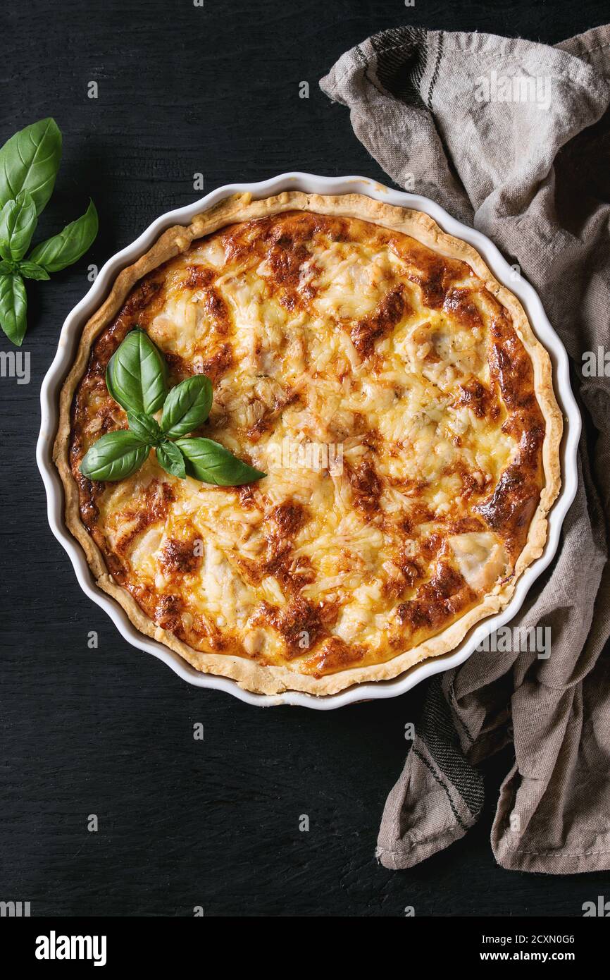 Baked homemade quiche pie in white ceramic form served with fresh