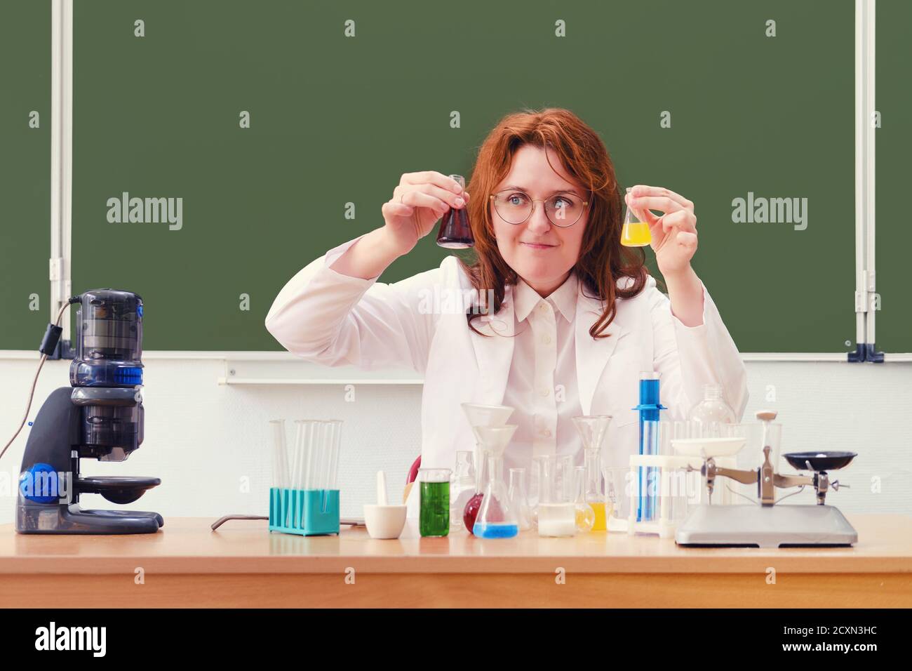 Chemistry teacher looks at reagent bubbles while sitting at a desk at