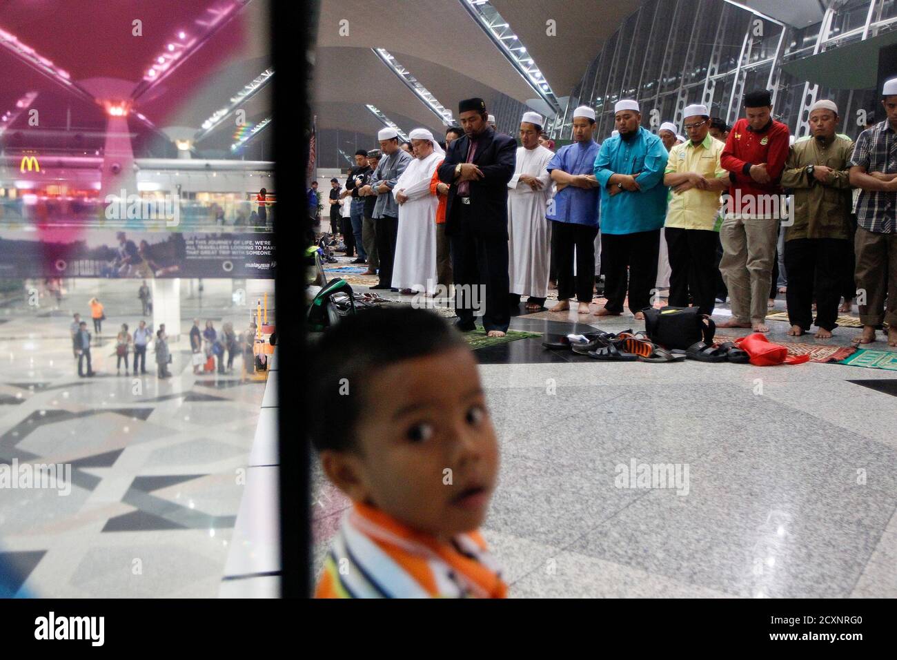 Muslims perform a special prayer for passengers of the missing Malaysia Airlines MH370 plane at the departure hall of the Kuala Lumpur International Airport March 13, 2014. Malaysian authorities said on Thursday there was no evidence that a jetliner missing for almost six days flew for hours after losing contact with air traffic controllers and continued to transmit technical data. REUTERS/Edgar Su  (MALAYSIA - Tags: TRANSPORT DISASTER RELIGION) Stock Photo