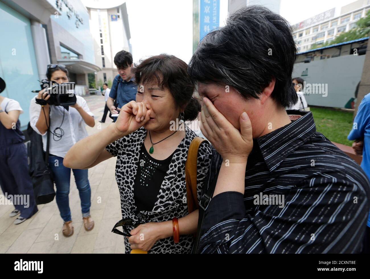 A woman (L), whose son, daughter-in-law and grandson were aboard the missing Malaysia Airlines flight MH370, cries after she and other family members failed to express their appeals to the airline outside its office in Beijing June 11, 2014. Months of searches have failed to turn up any trace of the missing Boeing 777, which disappeared on March 8 carrying 239 passengers and crew shortly after taking off from Kuala Lumpur bound for Beijing. REUTERS/Jason Lee (CHINA - Tags: TRANSPORT DISASTER) Stock Photo