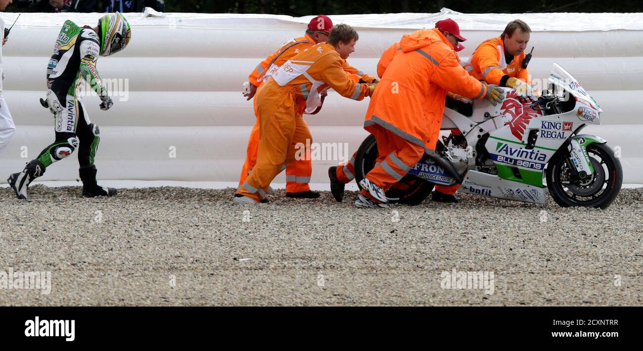 Track marshals push a bike of Avintia Racing MotoGP rider Hector Barbera  (L) of Spain after he crashed during the third free practice of the Czech  Grand Prix in Brno August 16,