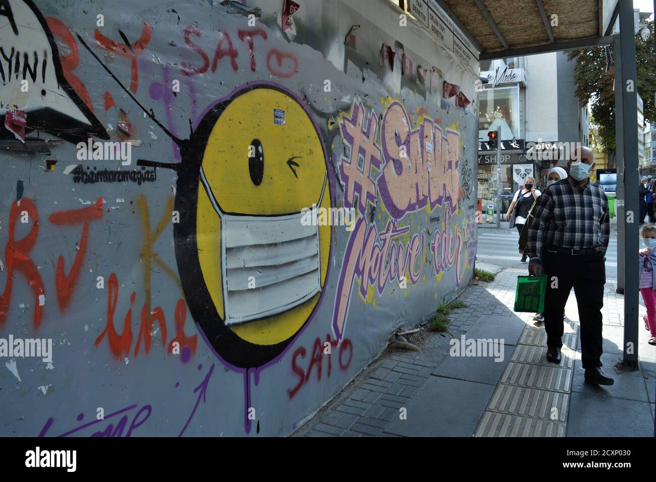 Ankara, Turkey. 1st Oct, 2020. A man wearing a protective face mask walks past a graffiti in Cankaya district amid the coronavirus (COVID-19) outbreak. Turkish Minister of Health Fahrettin Koca admitted on September 30 that asymptomatic cases of the coronavirus are deliberately excluded from daily reports. The minister's statement came after the revelation of a document showing nearly 20 times more cases than the official daily figures. Credit: Altan Gocher/ZUMA Wire/Alamy Live News Stock Photo