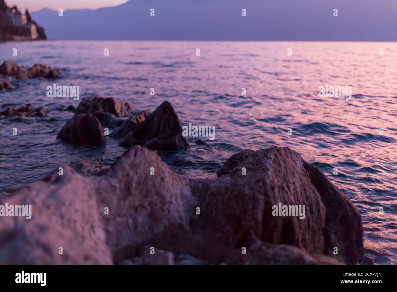 beautiful sunrise on lake garda went up with rocks and waves, with reflection of the colors of the sun Stock Photo