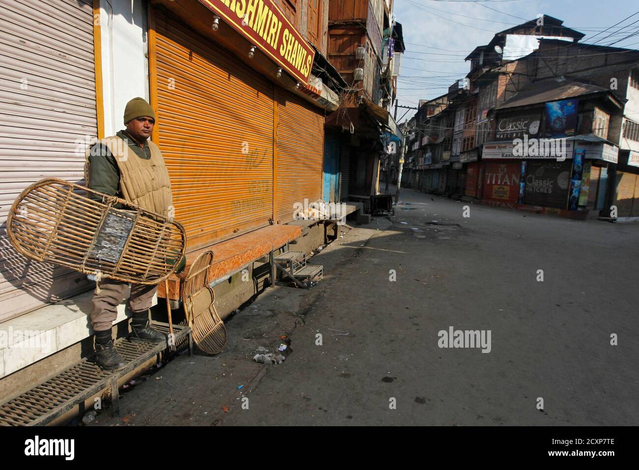 An Indian policeman keeps guard in front of the closed shops during a curfew in Srinagar February 12, 2013. India hanged Mohammad Afzal Guru, a Kashmiri man, on Saturday for an attack on the country's parliament in 2001, sparking clashes in Kashmir between protesters and police. Security forces had imposed a curfew in parts of Kashmir and ordered people off the streets. REUTERS/Danish Ismail (INDIAN-ADMINISTERED KASHMIR - Tags: POLITICS) Stock Photo
