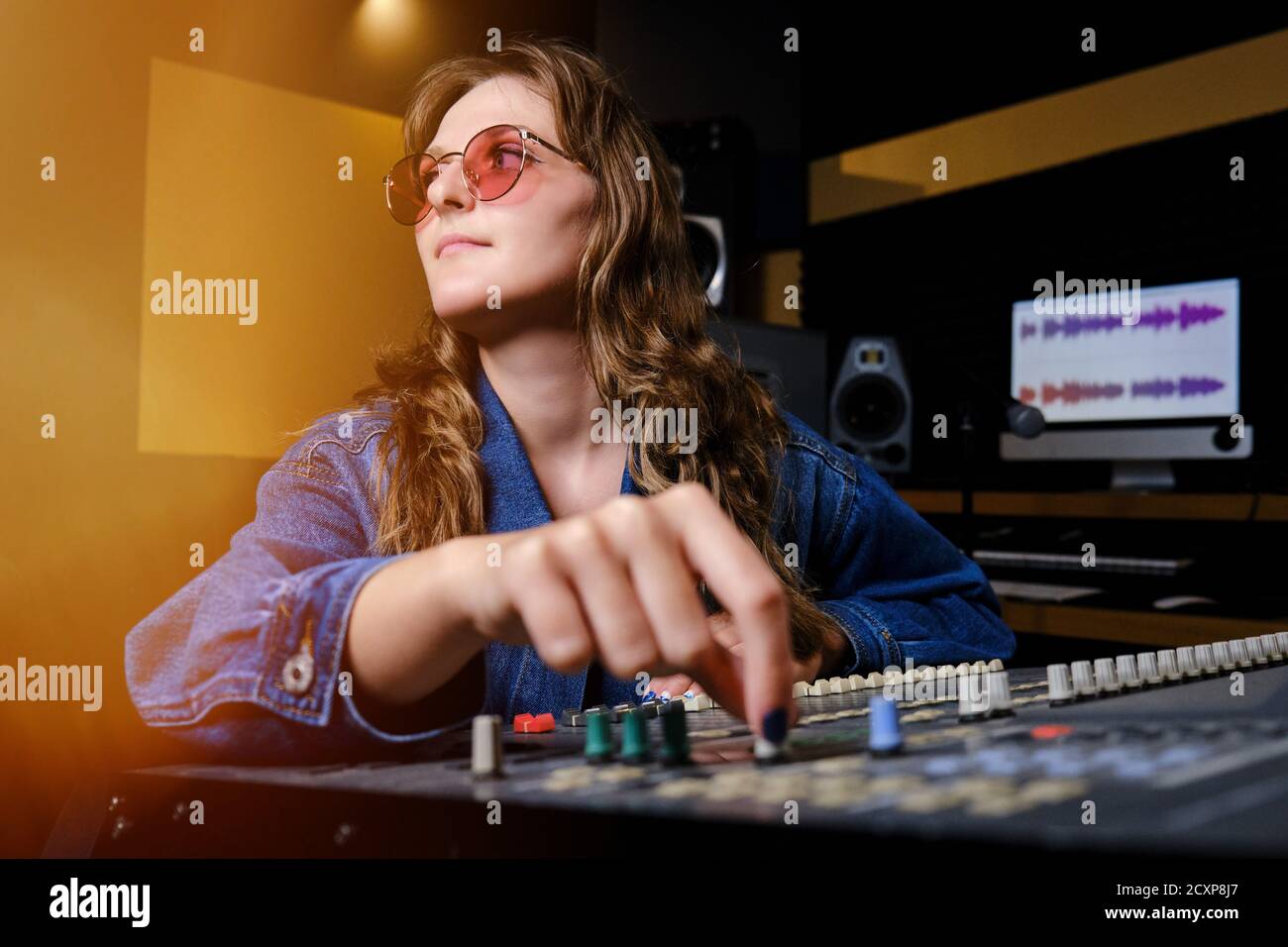 Woman sound engineer at the mixing Board. The girl at the remote in the recording Studio. Professional recording of musicians in the Studio. Stock Photo