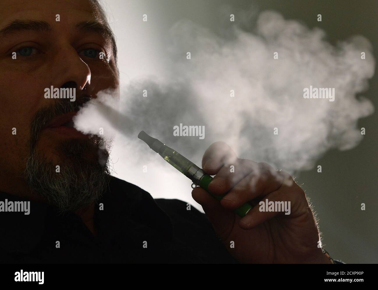 Gabor of 'smoke no smoke' puffs on an e-cigarette that his shop sells at in London 9, 2013. Puffing on slim metal tubes with pale yellow liquid, two