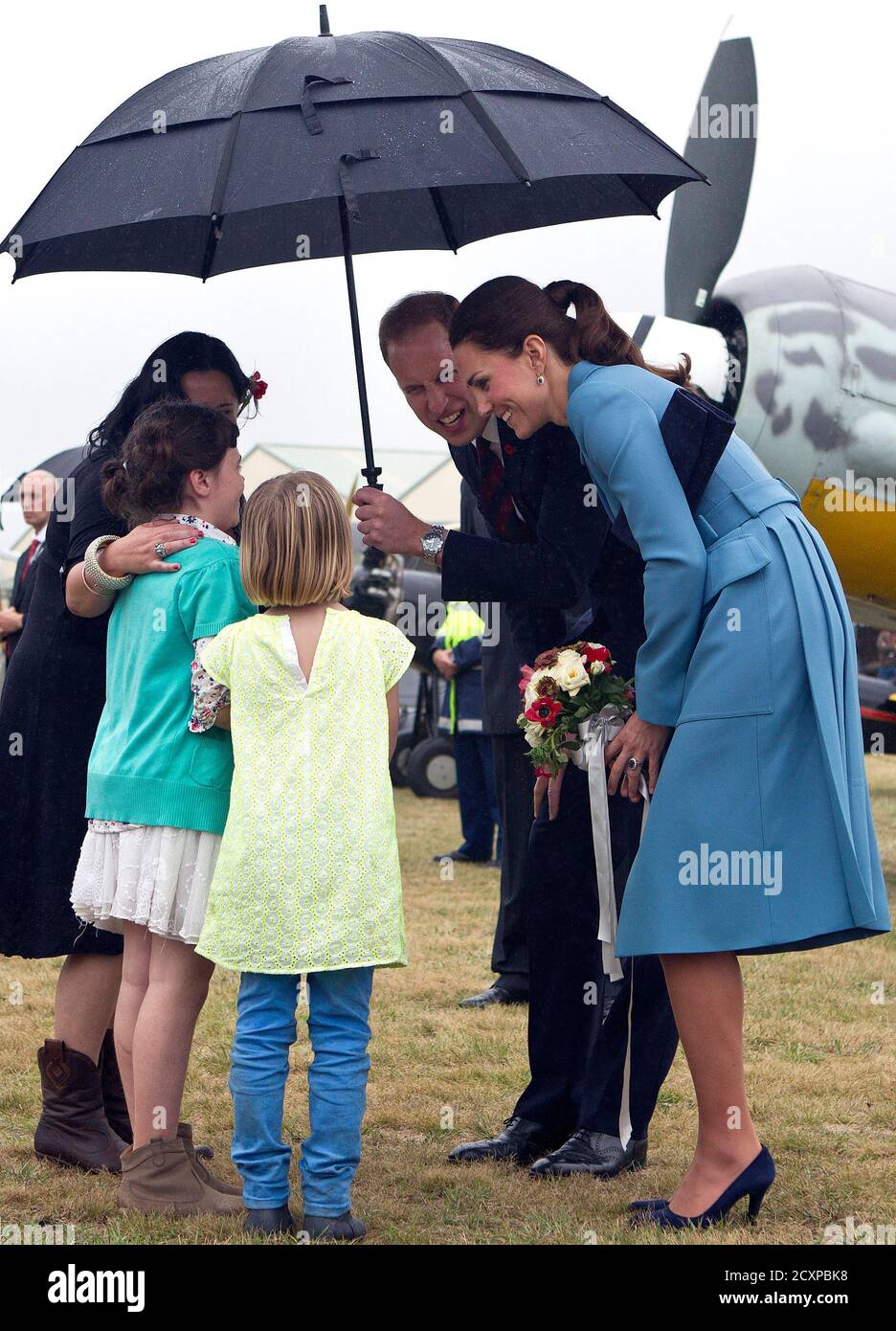 Britain's Prince William holds an umbrella above his wife Catherine ...