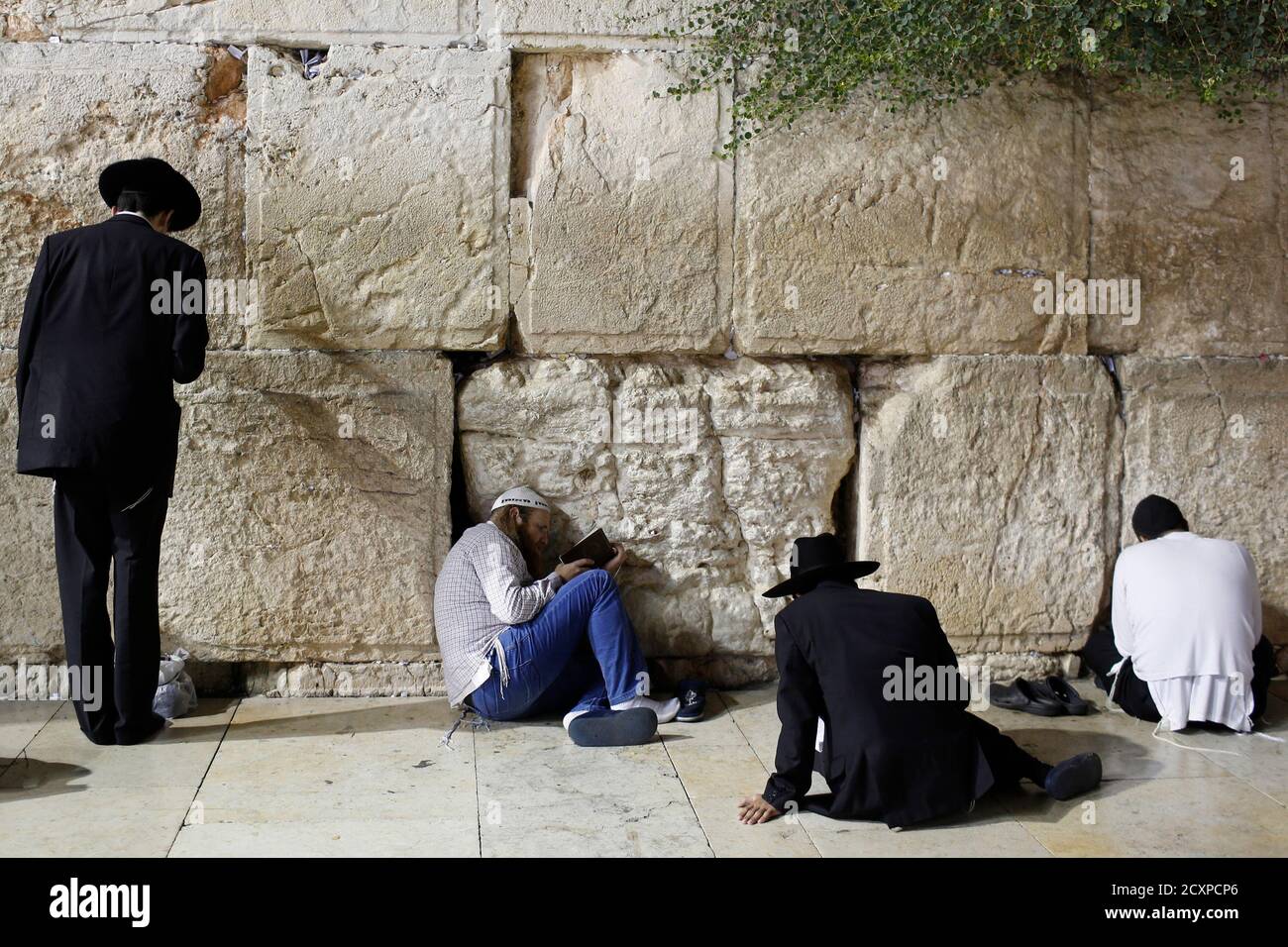 Jewish worshippers take part in prayers marking Tisha B'Av at the Western Wall, Judaism's holiest prayer site, in Jerusalem's Old City August 5, 2014. Tisha B'Av, a day of fasting and lament, commemorates the date in the Jewish calendar on which it is believed that First and Second Temples were destroyed in Jerusalem. REUTERS/Siegfried Modola (JERUSALEM - Tags: RELIGION) Stock Photo