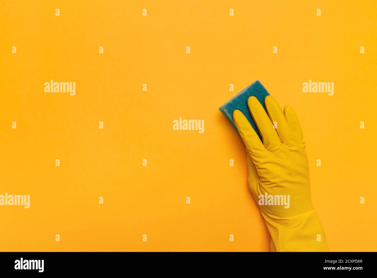 blue sponge in hand in rubber yellow gloves on a yellow background ...