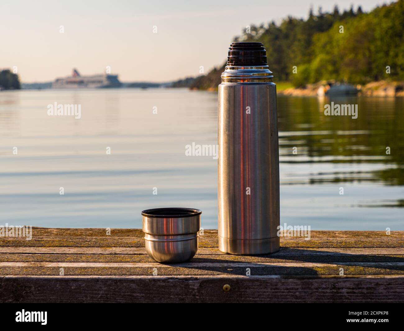 https://c8.alamy.com/comp/2CXPKP8/a-thermos-with-tea-on-a-wooden-bench-with-a-view-of-the-fjord-and-a-sailing-ship-in-the-baltic-sea-in-the-background-2CXPKP8.jpg