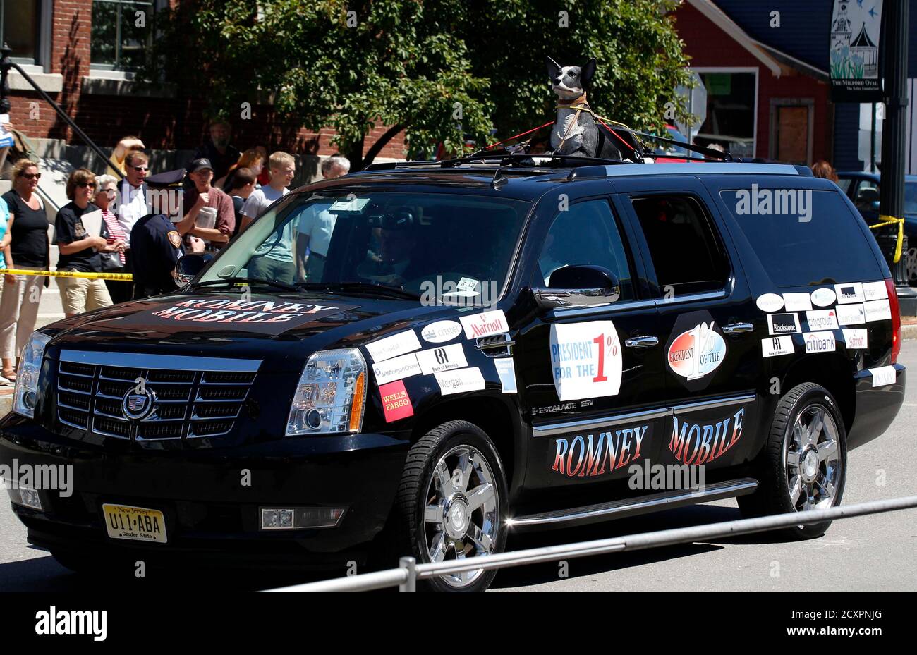 A car with a plastic dog strapped to the roof drives around the event site  before U.S. Republican Presidential candidate Mitt Romney speaks at an ice  cream social in Milford, New Hampshire,