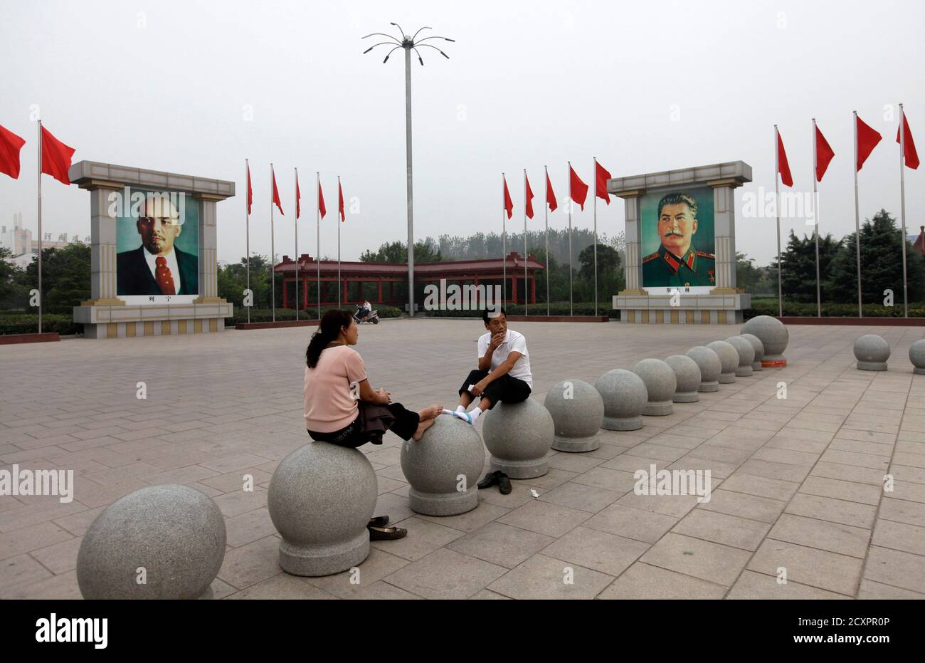 Residents rest near portraits of the Soviet state founder Vladimir Lenin (L) and dictator Joseph Stalin at Dong Fang Hong Square in Nanjie village of Luohe city in China's central Henan province September 24, 2012. Nanjie village, with more than 3,100 residents, is touted to be one of the remaining models of communist China, where the principles of morality and collectivism of the late Chairman Mao still strictly guide the people's daily lives. Aside from free housing, healthcare, food rations and education, locals working in the village's factories receive an average salary of 2500 yuan, abou Stock Photo