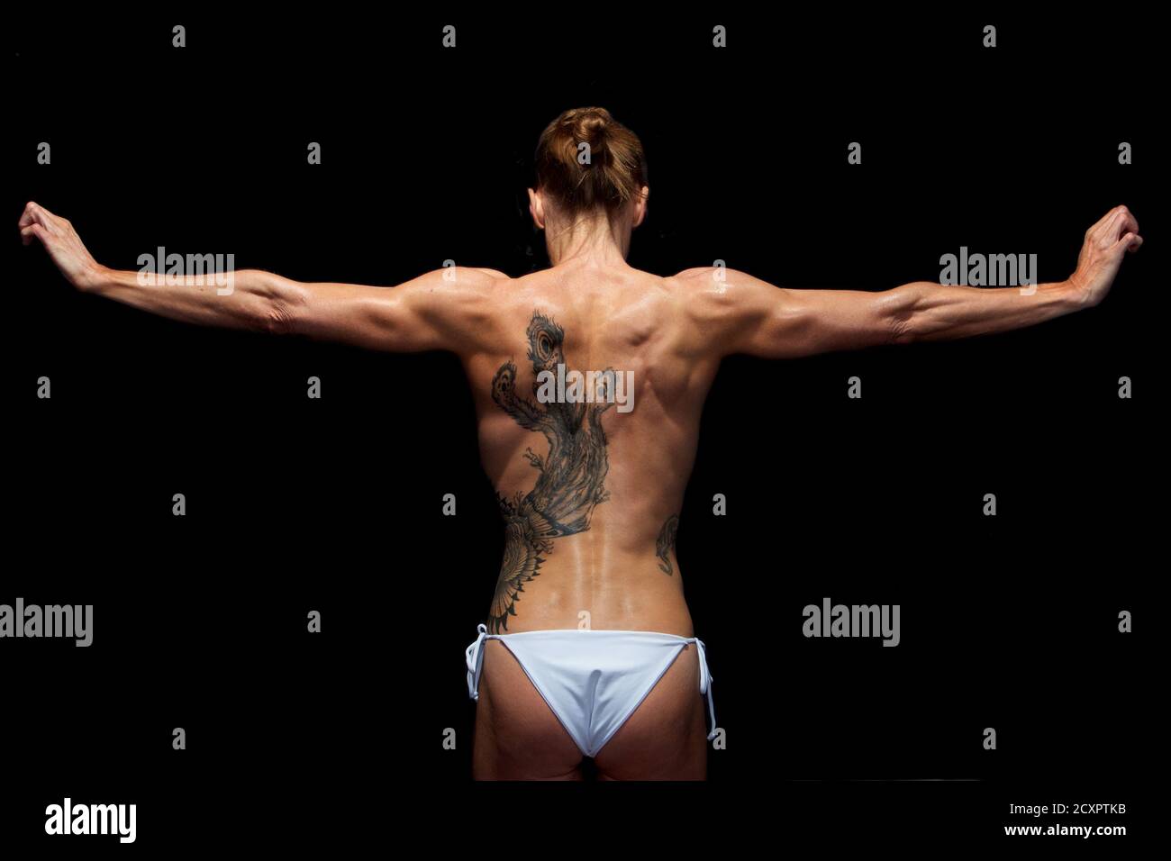 Forty year old woman showing off the muscles and large tattoo on her back Stock Photo