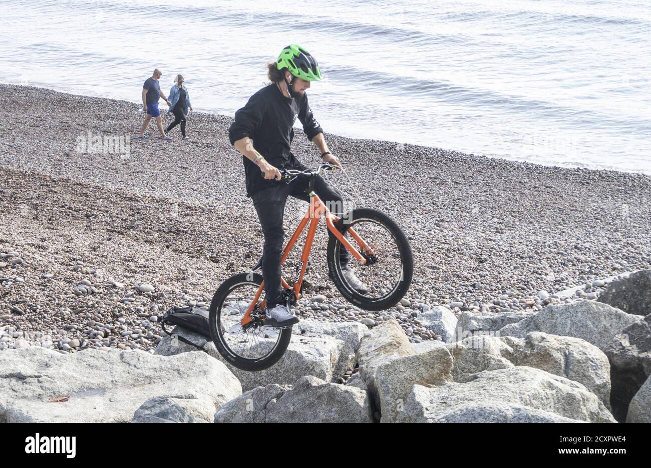 Sidmouth, Devon, 1st October 2020. A trials cyclist tests out his skills on the rock groynes at Sidmouth Devon as October begins on a bright and sunny day. Credit: Photo Central/Alamy Live News Stock Photo