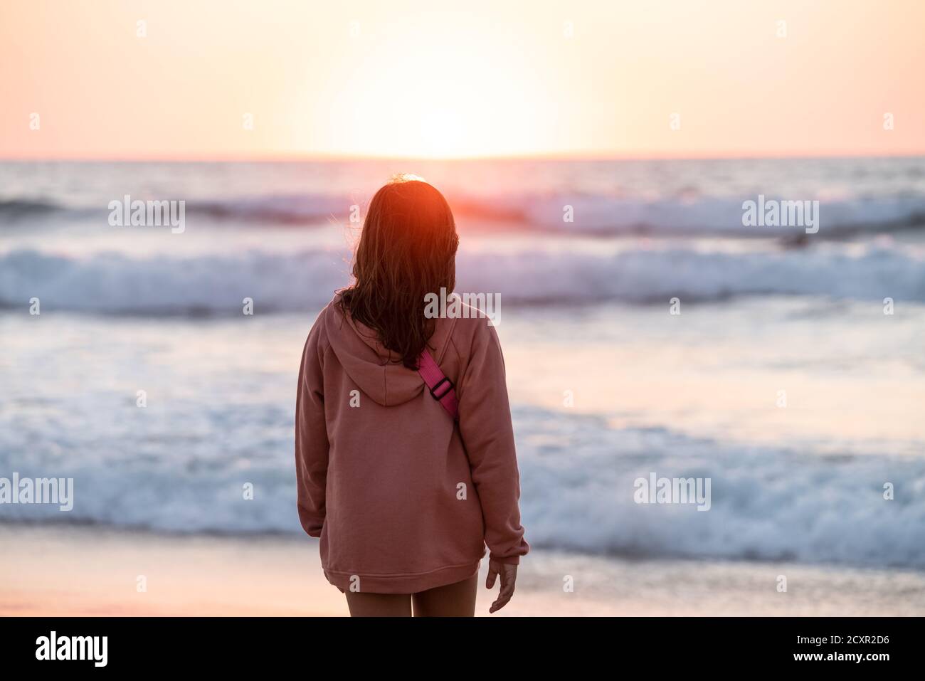 portrait girl in pink sweatshirt looking at the sea with a isolate ...