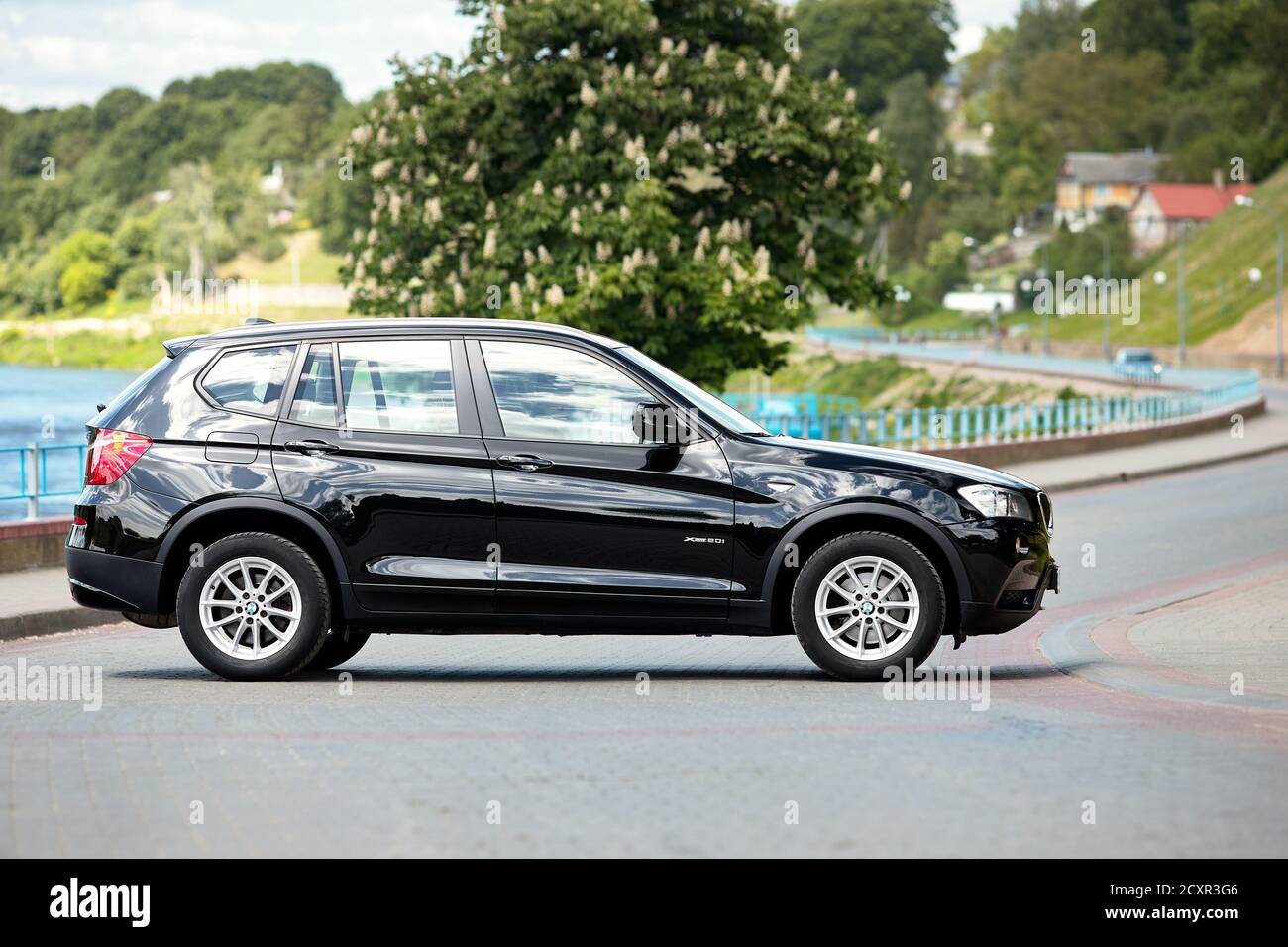 GRODNO, BELARUS - JUNE 2020: BMW X3 II F25 2.0i xDrive selective focus right side view outdoors on sunny road of summer city promenade with flowering Stock Photo