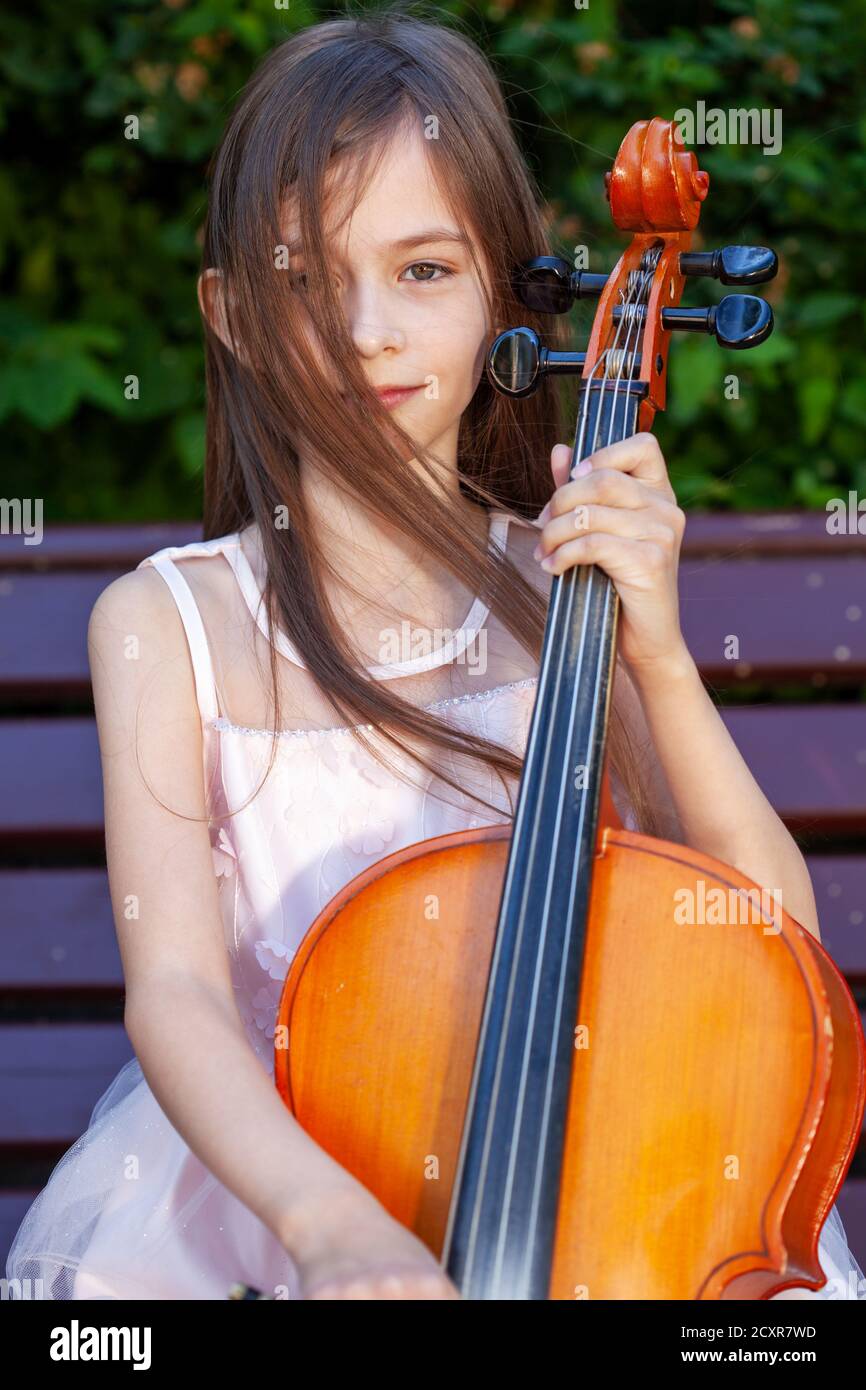 beautiful girl in a pink dress sits on a bench with a cello Stock Photo ...