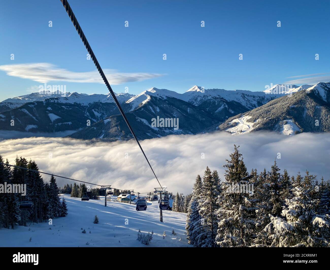 Scenic view from Schönleiten cable car ski lift to snow covered mountains and a blanket of clouds in the ski resort of Saalbach-Hinterglemm early in t Stock Photo