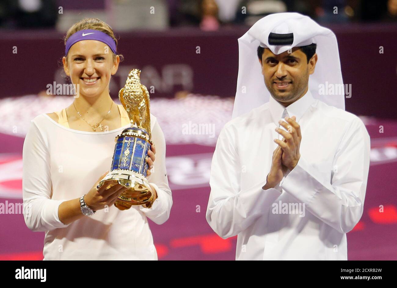 Victoria Azarenka (L) of Belarus holds her trophy beside President of the  Qatar Tennis Federation Nasser Al-Khelaifi, after defeating Serena Williams  of the U.S. in their women's singles final tennis match at