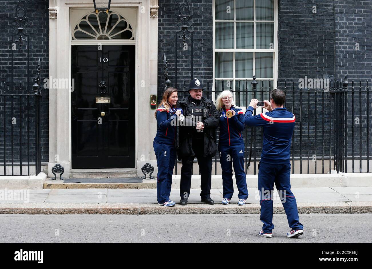 Britain's Paralympians Caroline Powell (L) and Kelly Gallagher pose with a police officer outside 10 Downing Street during a visit with the British 2014 Paralympic Winter Games team in London March 18, 2014. REUTERS/Suzanne Plunkett (BRITAIN - Tags: POLITICS SPORT OLYMPICS) Stock Photo