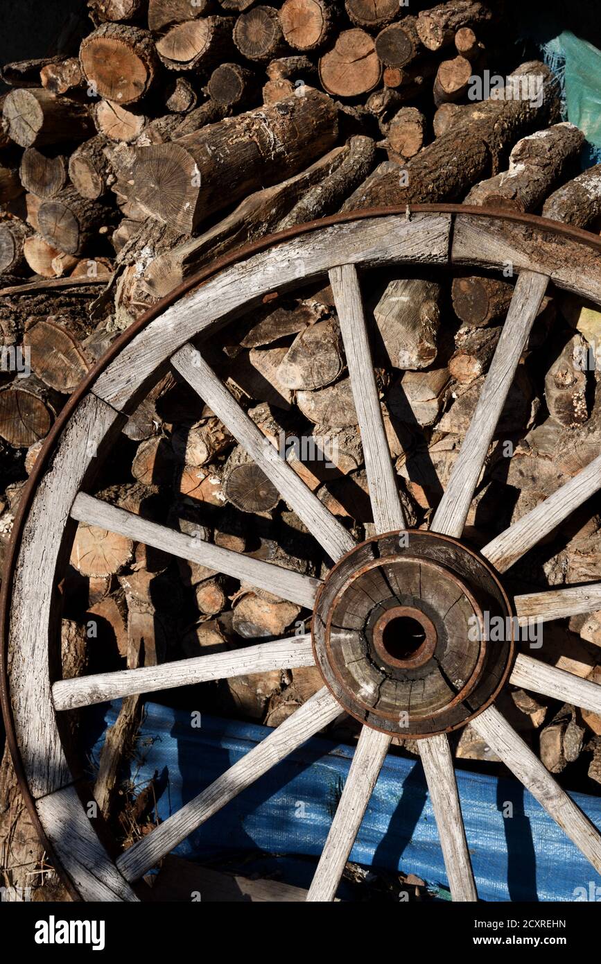Old Wooden Cartwheel with Reinforced Wooden Hub & Wooden Spokes & Chopped Firewood Stock Photo