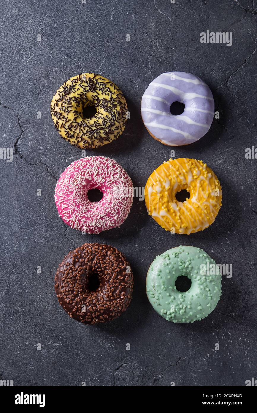 Variety of colorful glazed donuts over black texture background. Top ...