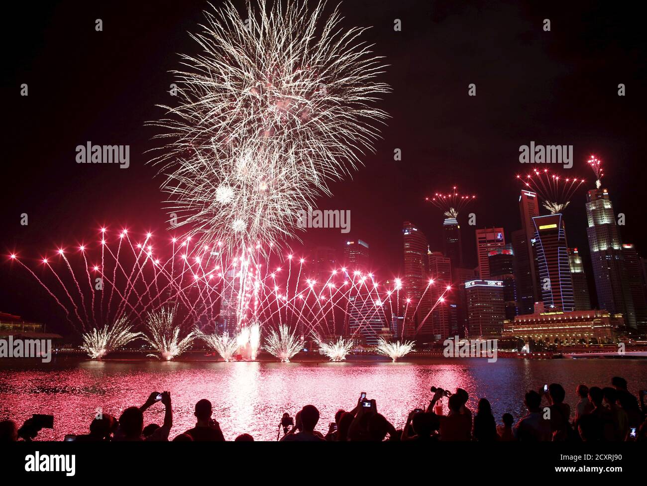 People take photos of fireworks in the skyline of Singapore during a National Day Golden Jubilee parade rehearsal July 25, 2015. The city-state's 50th independence falls on August 9. REUTERS/Edgar Su Stock Photo