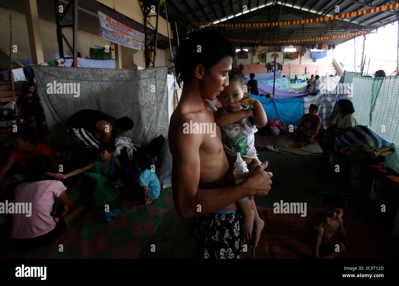 A man carries his child at an evacuation centre for flood victims in Calumpit, Bulacan, north of Manila, August 22, 2013. The southwest monsoon that wreaked havoc on Metro Manila and nearby areas earlier this week is likely to weaken now that Typhoon Trami made landfall over China, state weather forecasters said Thursday. The death toll from the heavy monsoon rain and floods since last weekend rose to at least 16 as of Thursday morning, the National Disaster Risk Reduction and Management Council said.  REUTERS/Erik De Castro (PHILIPPINES - Tags: DISASTER ENVIRONMENT) Stock Photo