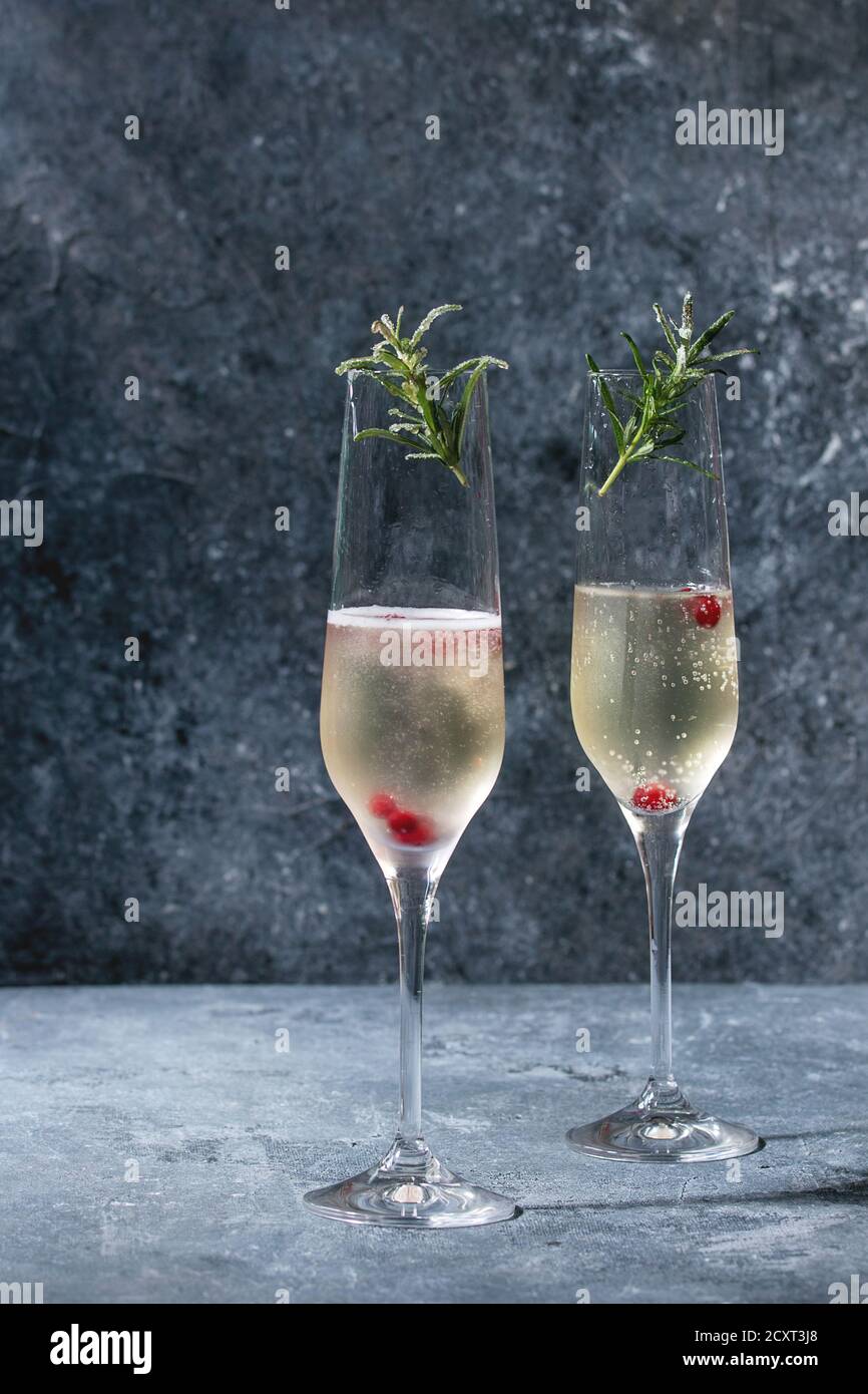 Two glasses of white champagne served with red berries and rosemary over blue texture background. Copy space Stock Photo