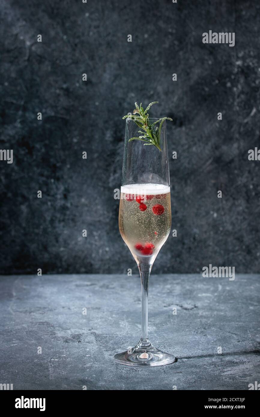 One glass of white champagne served with red berries and rosemary over blue texture background. Copy space Stock Photo