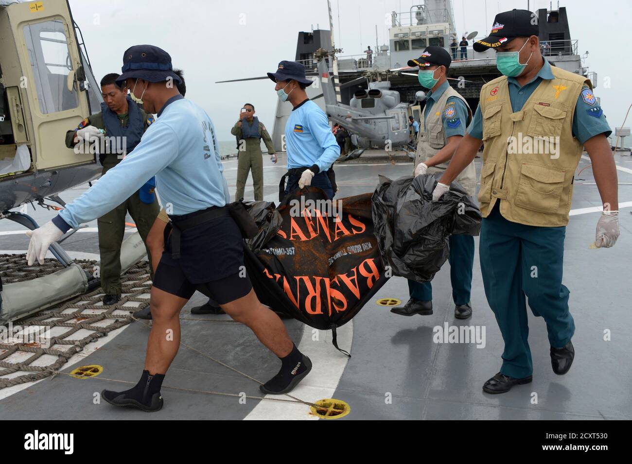 Indonesian Navy personnel carry body bags containing dead bodies of  passengers from AirAsia flight QZ8501, to a Navy helicopter on the  Indonesian Navy vessel KRI Banda Aceh, at sea January 3, 2015.