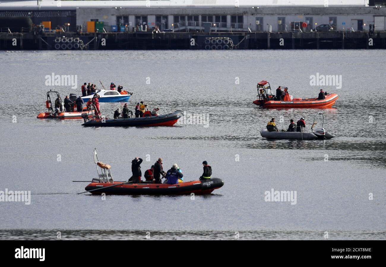 Boats travel along together passed HMNB Clyde at Faslane to try and move a bottlenose whale from the Gare Loch. Rescuers from British Divers Marine Life Rescue Medics (BDMLR) are using boats in an attempt to herd a pod of northern bottlenose whales out of Loch Long amid concern over the potential impact from Exercise Joint Warrior, a major international military exercise planned for the area, as whales are particularly sensitive to underwater sounds. Stock Photo