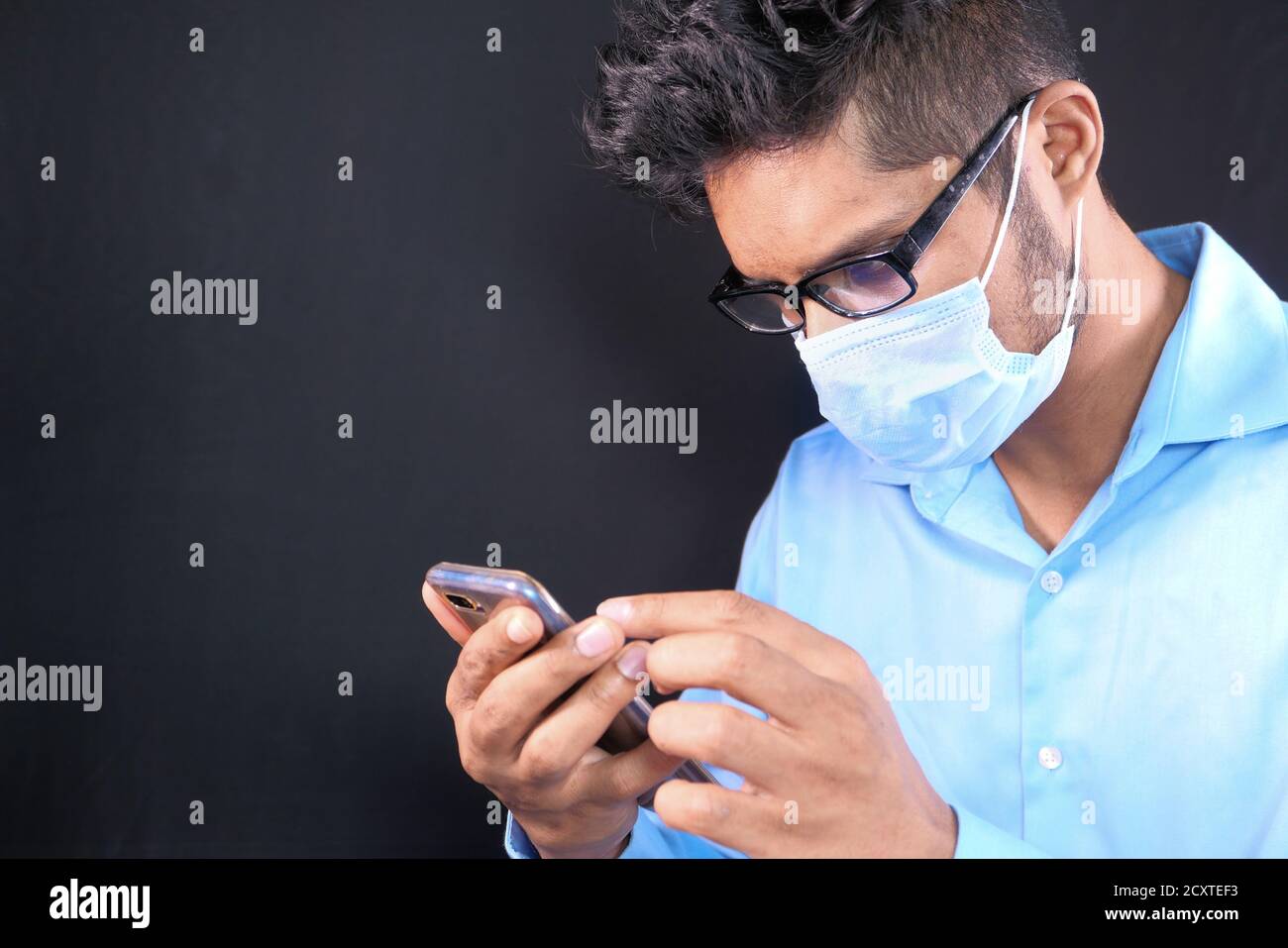 young man in face mask using smart phone on black background  Stock Photo