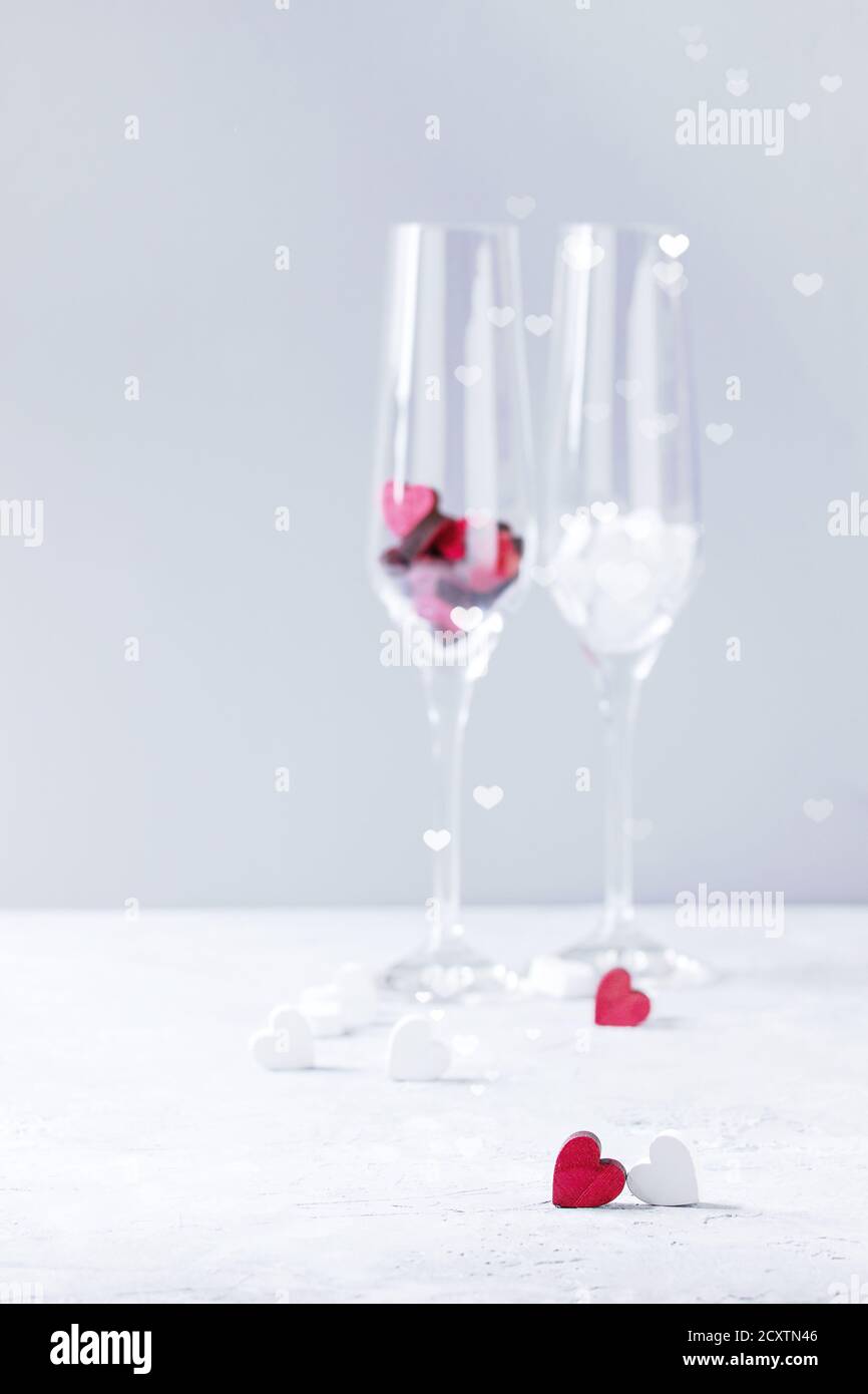 Love Valentine day greeting card with two empty champagne glasses and wooden hearts over white gray background. Copy space. Selective focus Stock Photo