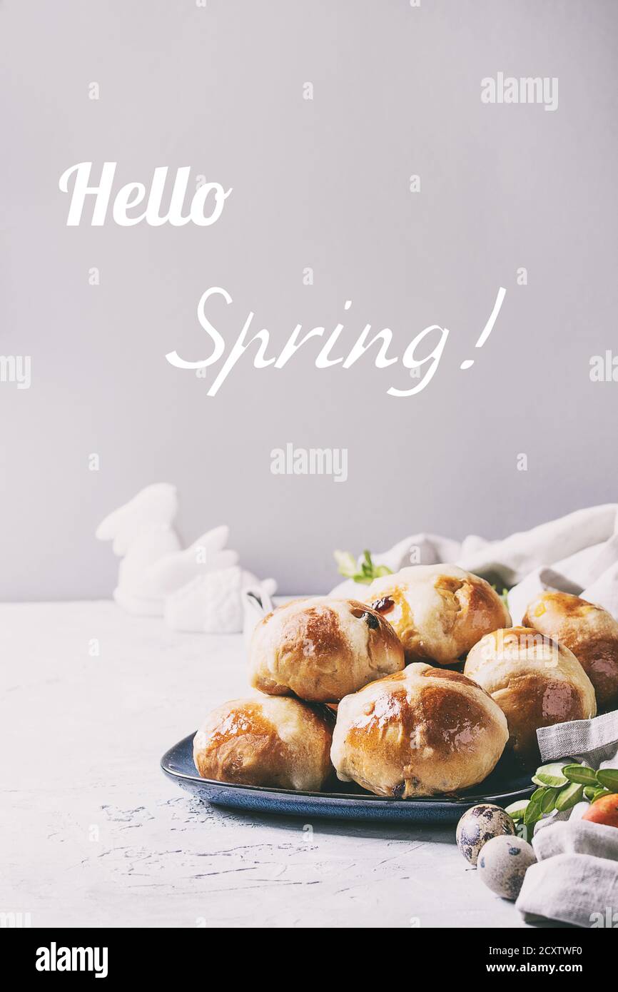 Homemade Easter traditional hot cross buns on blue plate with textile and colored quail eggs over white texture background. Copy space Hello spring te Stock Photo