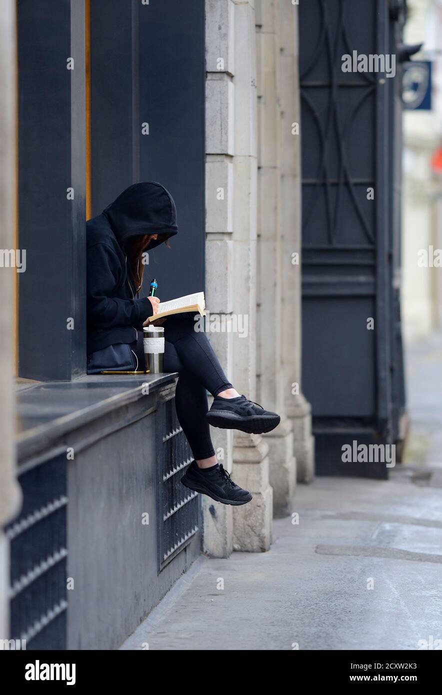 London, England, UK. Young woman reading a book and vaping in Covent Garden Stock Photo