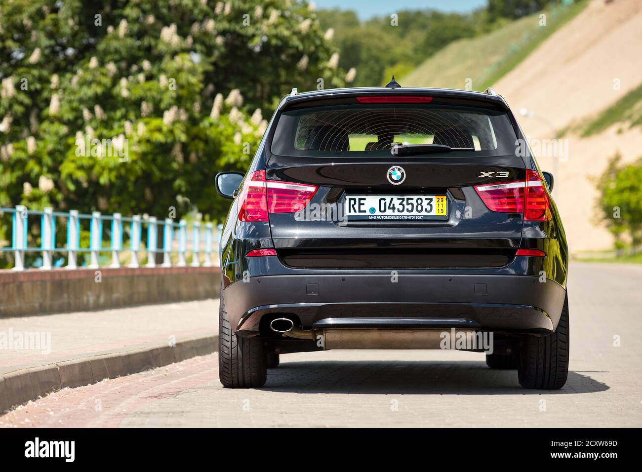 GRODNO, BELARUS - JUNE 2020: BMW X3 II F25 2.0i xDrive selective focus down back view with wheels turned outdoors on sunny road summer city promenade Stock Photo
