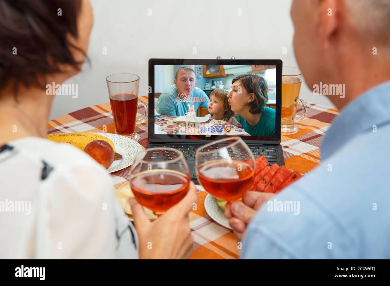 Parents celebrate the girl's birthday through a video call of a virtual party with grandparents. Stock Photo